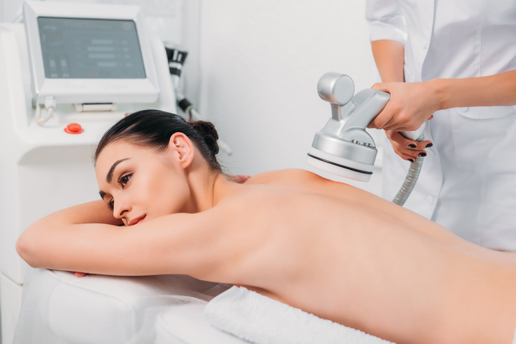 attractive woman on massage table getting electrical massage done by cosmetologist in spa salon